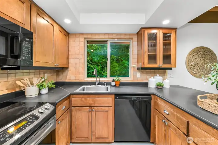 The kitchen overlooks the surrounding greenery, offering ample workspace, plentiful storage, and easy connection to the main living areas. The kitchen overlooks the surrounding greenery, offering ample workspace, plentiful storage, and easy connection to the main living areas.