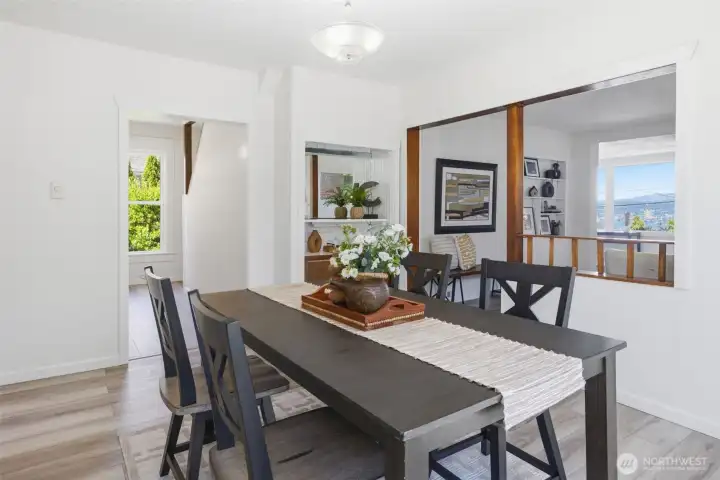 Spacious view from the dining room into the living area, with access to a bedroom and stairs leading to the upper-level bedrooms and basement.
