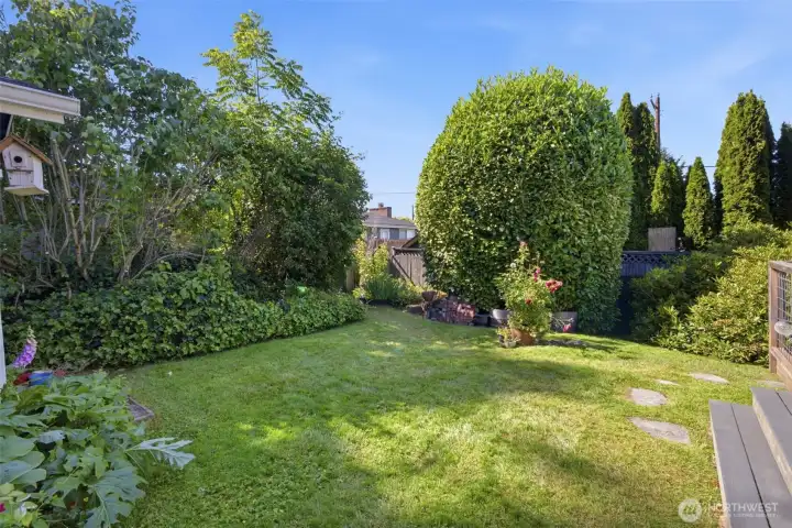 The private fully fenced back yard with established plantings with room for play space off the deck.
