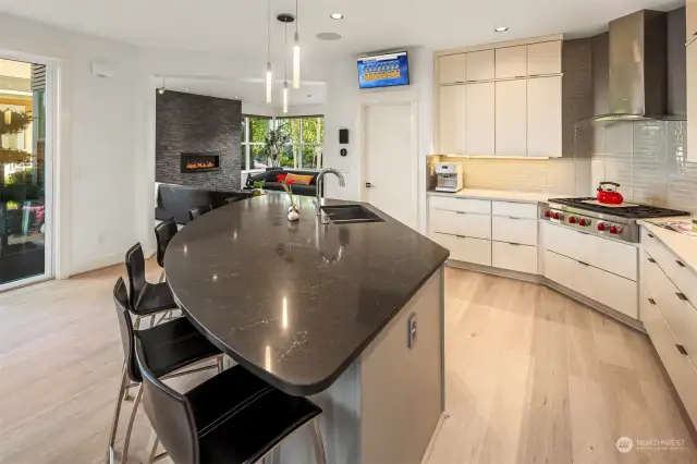 Open concept kitchen, living, dining connected to side yard patio! Island with six seating spaces.  Quartz counters, glass tile backsplash.  High-end appliances by Wolf and Sub-Zero.  Walk-in pantry.