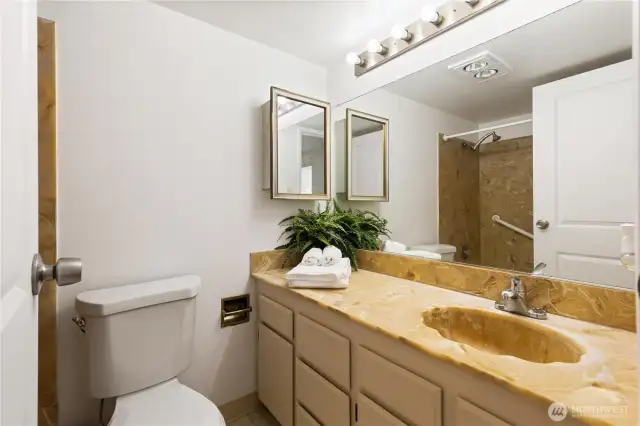 Primary bathroom with stone counters with new lighting and paint