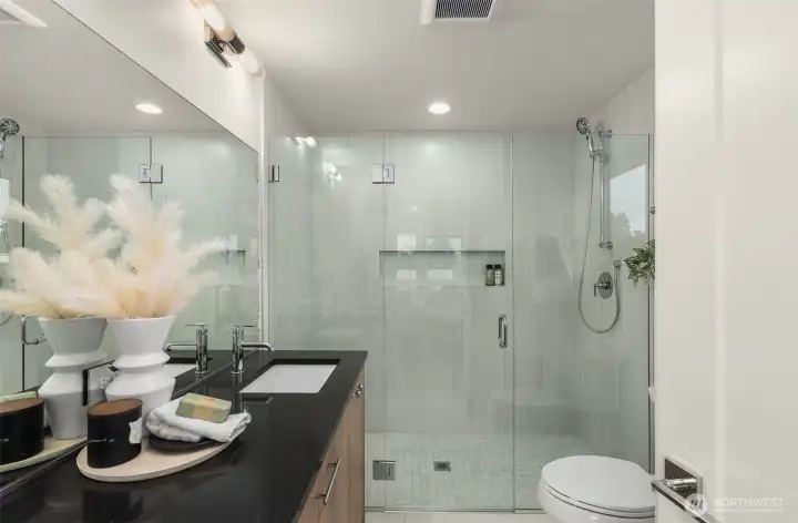 With glass shower, designer tile, and modern lighting, this bathroom turns everyday routines into moments of luxury. Photos are of model home with similar fixtures & finishes.