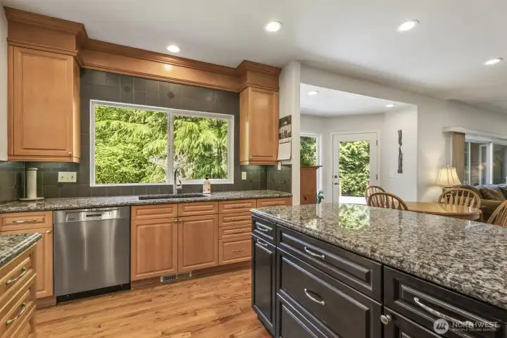 The informal areas are one contiguous space and feature an updated kitchen with maple cabinets with soft close drawers and doors, slab granite counters, an island with seating, stainless steel appliances including a gas range and a walk-in pantry.