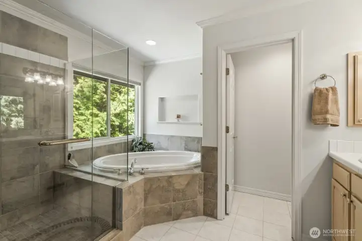 The primary suite with crown molding and tranquil backyard views features 2 walk-in closets and an updated 5 piece bathroom with soaking tub, tiled shower, dual vanities and tile floor.