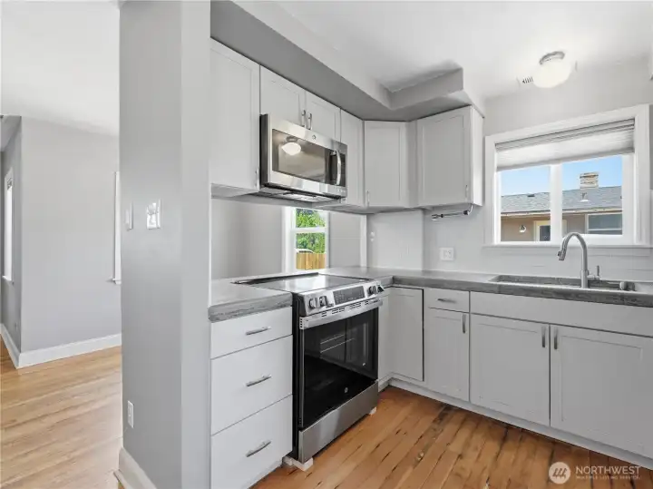 Kitchen with new stove, concrete counters and glass tile backsplash.