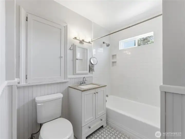 Main floor remodeled bath with tile flooring and tile tub surround.