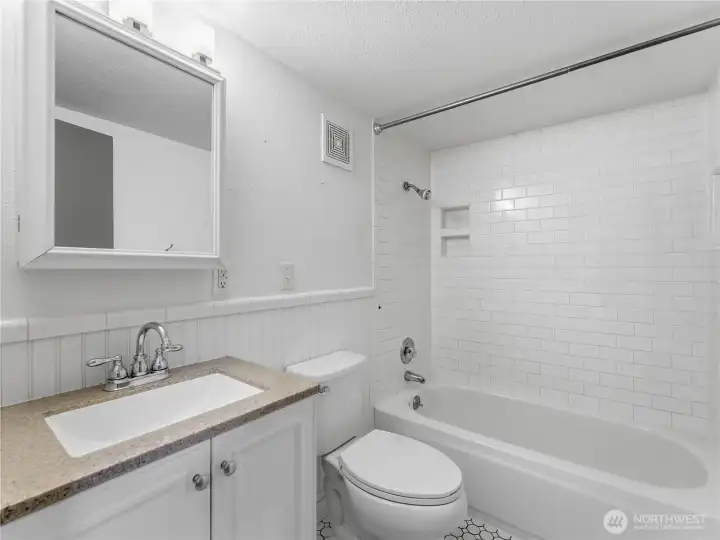 Lower bath remodeled with tile floor and tile tub surround.