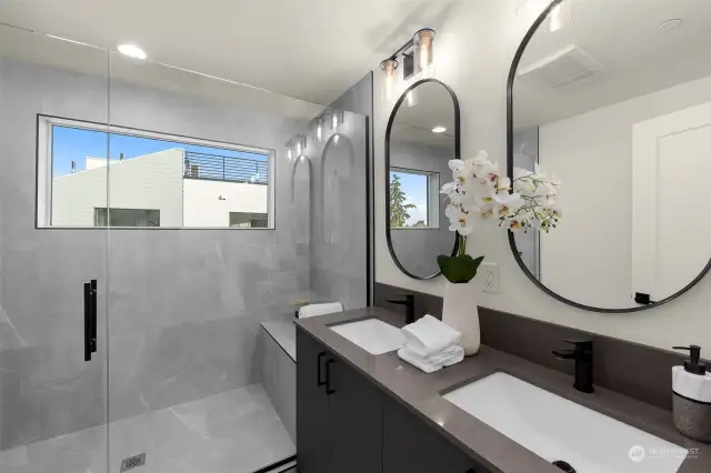 Step into luxury in the spa-inspired primary bathroom, where sleek double vanities and a glass-enclosed rain shower create a serene retreat.