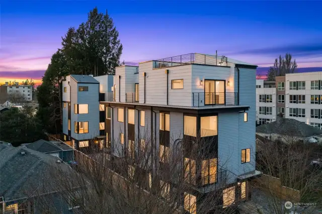 A stunning exterior view showcasing sleek architecture and multiple balconies, crowned by a rooftop deck for sunset views.