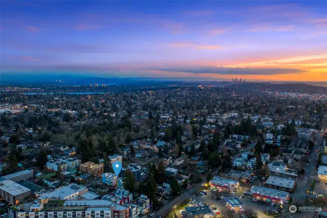 A breathtaking aerial shot of the surrounding neighborhood showcasing the property's location amidst a dynamic cityscape. The evening lighting emphasizes the vibrancy and accessibility of nearby amenities.