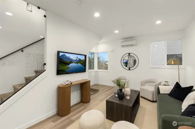 Catch up on your favorite shows or unwind after a long day in this cozy yet stylish living area, enhanced by oversized windows that frame the surrounding greenery.