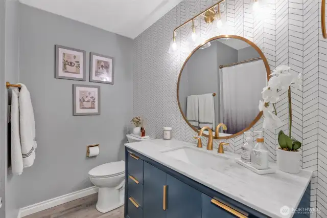 Newly remodeled bathroom with trendy wallpaper and fixtures.