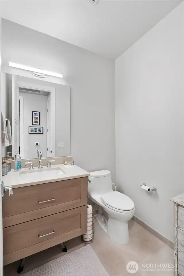 Style and utility for everyday living.  The powder room is fresh, bright, and effortlessly modern. Ideal for guests or quick use throughout the day, it reflects the same elevated design found throughout the home, with soft-close cabinetry, updated fixtures, and durable tile underfoot.