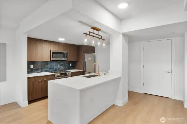Sharp design in shared spaces.  Even the shared amenities echo the attention to detail found throughout the building. This designer kitchen features warm wood cabinetry, a statement backsplash, and brass fixtures—all part of a cohesive, elevated community experience. Entertain, connect, or just cook up something special in style.