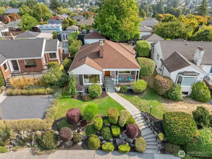 Mature plantings, manicured shrubs, and vibrant greenery create year-round curb appeal, with a curved walkway leading to the entry for a polished, inviting approach.