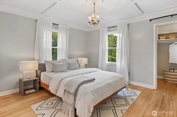Serene primary bedroom with cove ceiling trim detail and abundant natural light.