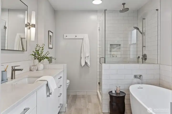 Spa-inspired primary bath featuring a freestanding soaking tub, frameless glass shower with rain shower head, vanity with quartz counters, and designer tile finishes—bright, modern, and luxurious.