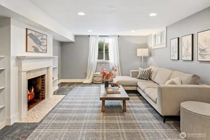 Spacious lower-level family room with wood-burning fireplace, built-ins, and natural light—ideal for media and play. Doubles as a private living room retreat for visiting guests.