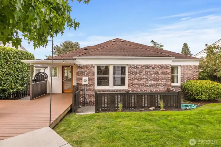 Private backyard retreat with spacious entertaining deck, string lighting, and level lawn—perfect for outdoor dining, play, and gatherings.
