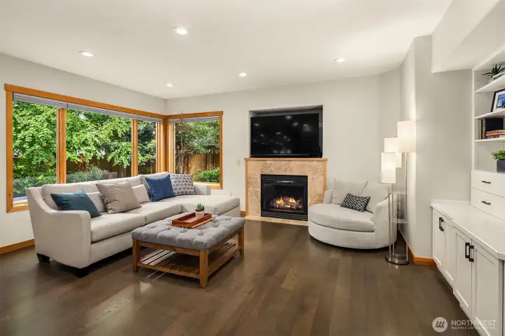 White Oak hardwood floors flow throughout the main level into a spacious family room with one of two fireplaces with travertine tile surround, built-in bookcases, cabinets and views to the outdoor space.