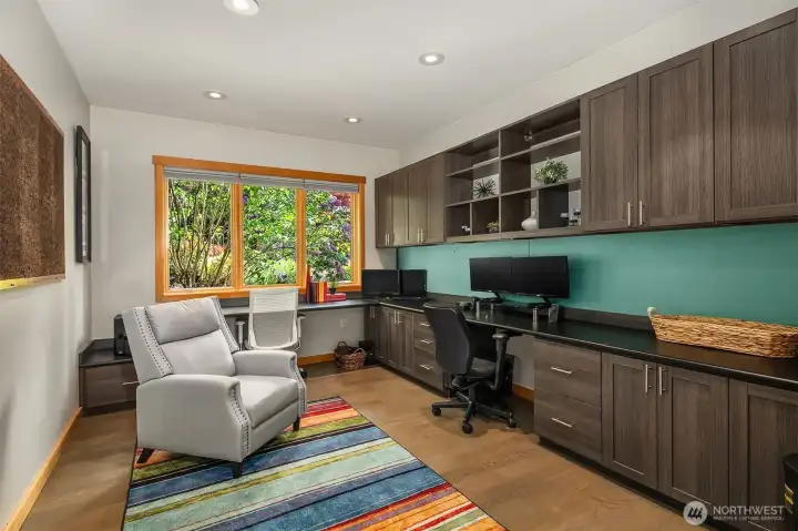 A large main-level den/office with French doors and features built-in desk and cabinet space.
