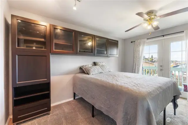 Second bedroom features built-in cabinets, deck access and ample closet space.