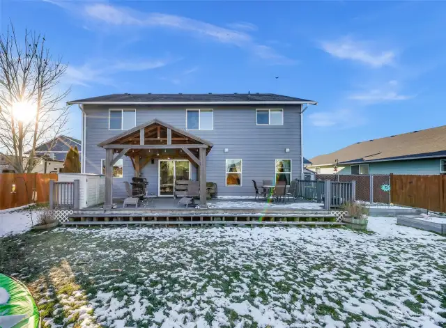 A blue sky view from the backyard showcasing it’s spacious lot and outdoor features.