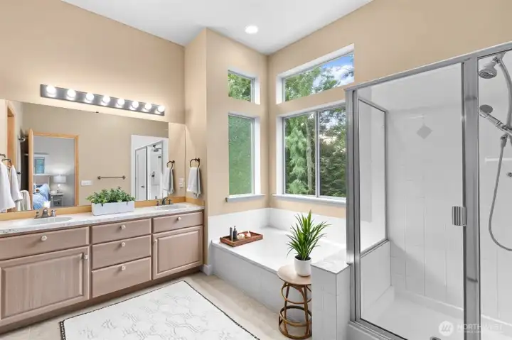 Luxurious primary bath with dual vanities, a soaking tub, and a separate glass shower.