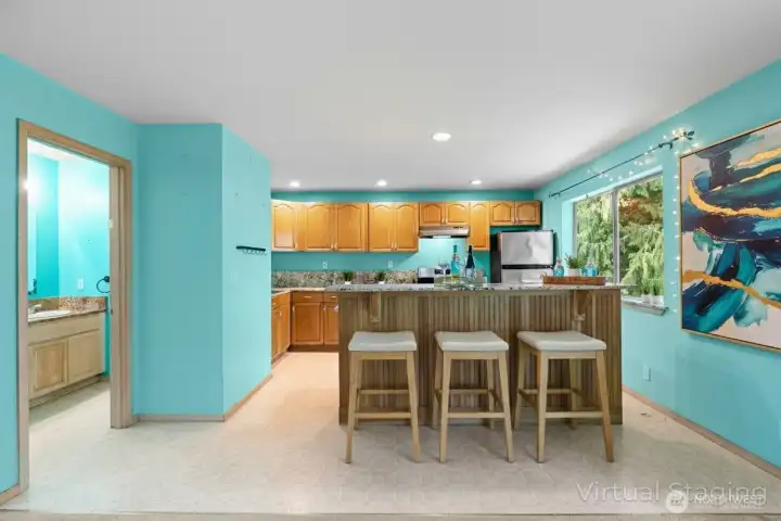 Open-concept downstairs living space with kitchen and cozy lounge area. (Virtually Staged )