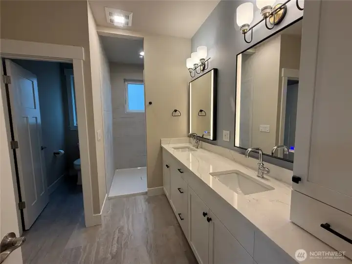 Primary Bathroom with tile shower, separate commode room, double sinks, granite counters, dual lighted and fog control mirrors