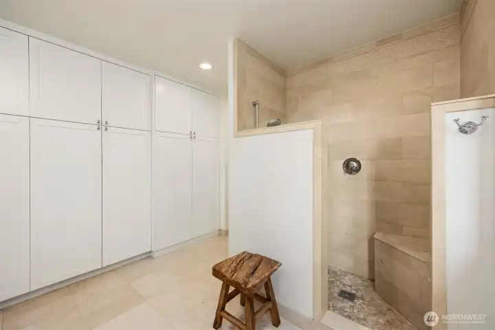 A wall of closet space and spacious shower with bench seat grace the bathroom.