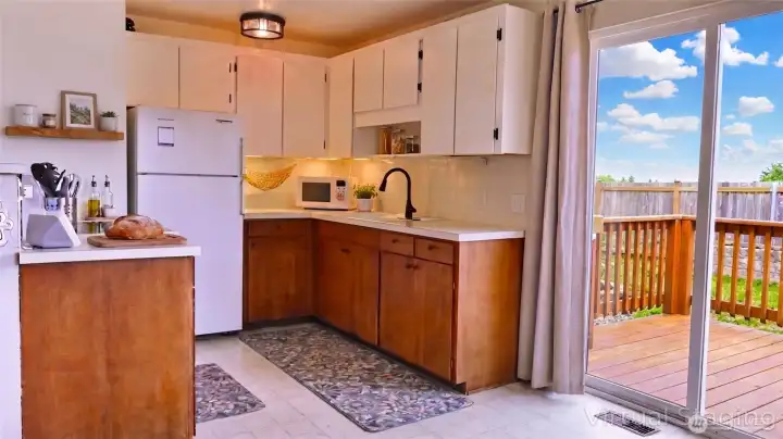Light-filled kitchen with a functional U-shaped layout, contrasting cabinetry, and direct access to the deck—bringing in sunshine and effortless indoor-outdoor flow.