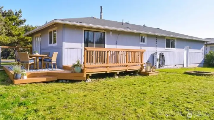 Spacious backyard with a wide lawn and a sunny deck that’s perfect for outdoor dining and casual gatherings.
