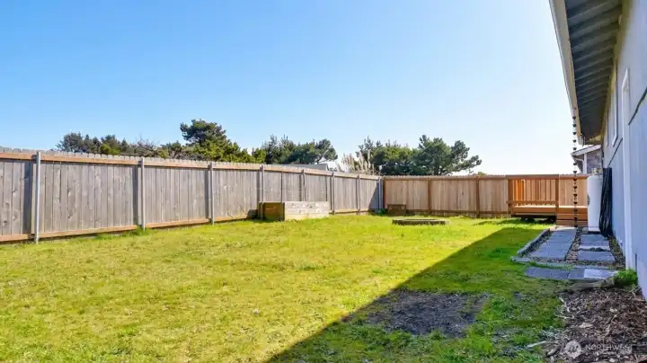 Level, fenced backyard with clean lines and room to customize, framed by coastal trees for a relaxed outdoor setting.