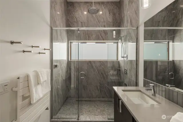 Spacious walk-in shower with rain shower, body sprays and detachable shower head is high tech and all digitally controlled! Large frosted window, floor-to-ceiling designer tiles, large tempered glass door and radiant wall heater that doubles as a towel warmer all enhance the spa-like feel of this bathroom.