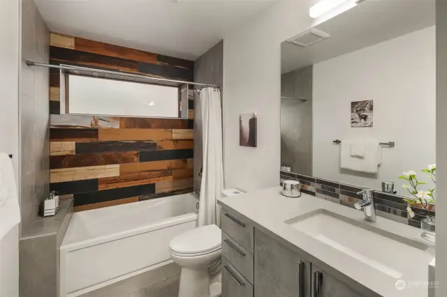 Lower level full bathroom features a floating vanity, large ceramic floor tiles and custom tub-to-ceiling designer tile  surround.