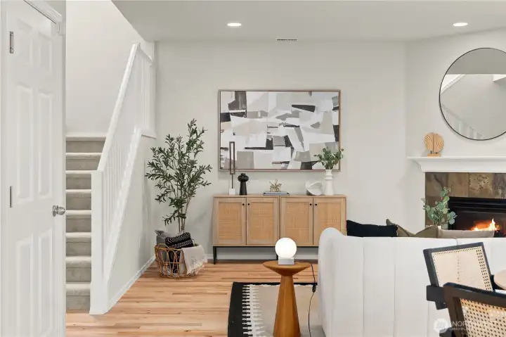 A welcoming casual dining and living area offers an open, connected layout ideal for everyday living and entertaining. The living space is anchored by a cozy corner gas fireplace, creating a warm focal point, while a classic spindle staircase adds architectural charm and visual interest. Seamlessly connected to the kitchen, the layout allows for easy flow between spaces, with direct access to a private outdoor patio—perfect for indoor-outdoor living and relaxed gatherings.