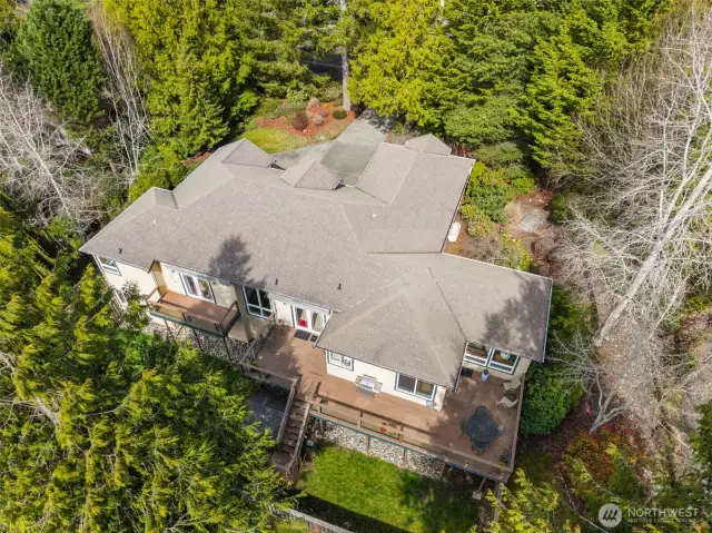 An aerial view highlights the native trees and landscape surrounding this beautiful half-acre property .