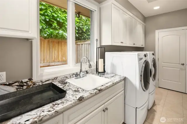 Massive laundry area just off the 3 car garage with slab counters, sink and Whirlpool washer and dryer.