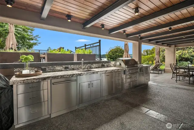 The party always starts in the kitchen and this fine lakefront residence boasts 2 kitchen. This over the top perfect outdoor commercial kitchen boasts a Lynx Grill, burners and warming drawer, a full suite of stainless steel cabinets, sink, Asko outdoor dishwasher and scads of slab granite counters!