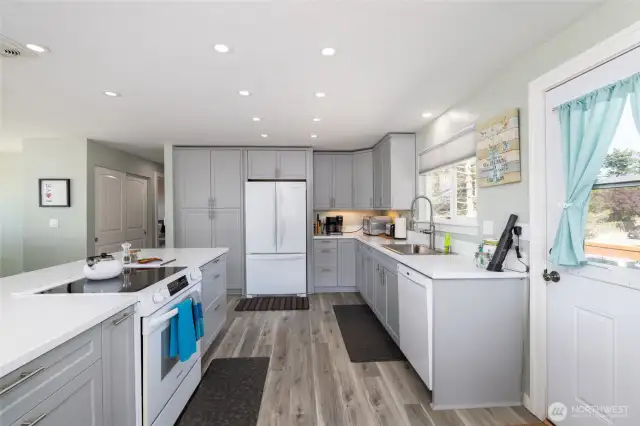 Back entrance opens to updated kitchen with quartz counters, new cabinetry and family room with views