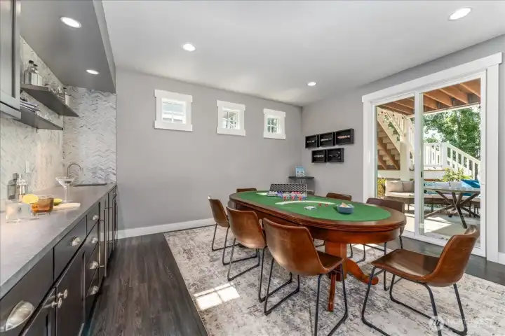 Main floor game room and bar kitchenette and sliding doors leading to the outdoor patio with private spa, fire pit & lounge area.