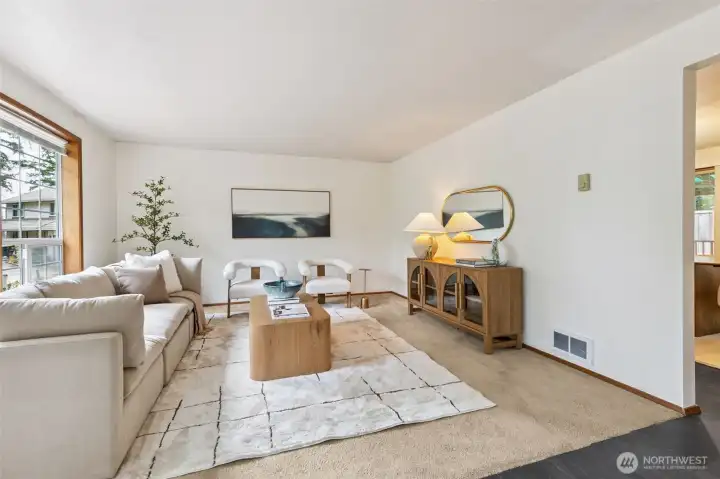 Spacious and serene living room featuring large windows for abundant natural light, soft neutral furnishings, and a warm, inviting layout perfect for gathering or relaxing.