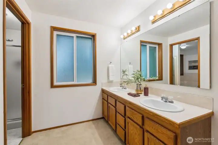 Spacious primary bathroom featuring a large dual-sink vanity, generous counter space, and a separate shower area for added convenience.