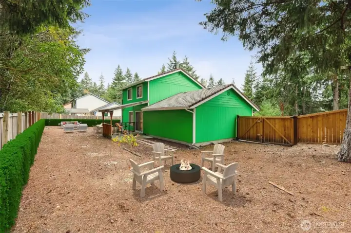 Expansive, fully fenced backyard offering ample room to play, garden, or create your ideal outdoor retreat. Mature evergreens frame the space for added privacy and a peaceful natural backdrop. A side gate provides convenient access, and the covered back porch extends your living space for year-round enjoyment. Virtually staged.