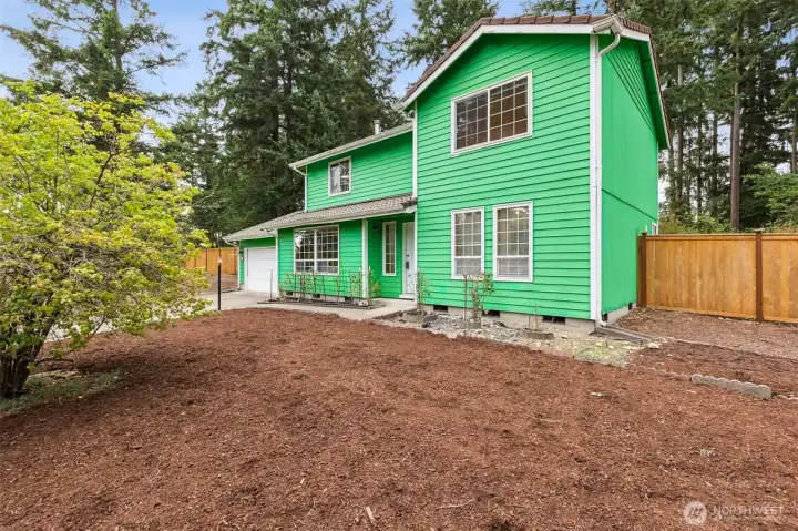 Fresh landscaping and mature evergreens frame this welcoming two-story home. The spacious front yard offers plenty of room for gardening, play, or future personal touches, while the fenced surroundings provide privacy and a peaceful natural backdrop. A charming covered entry adds to the home’s inviting presence.