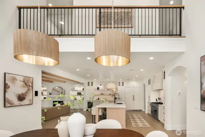 Light-filled dining area featuring soaring over 18 foot ceilings and open sightlines visible from the upper level.
