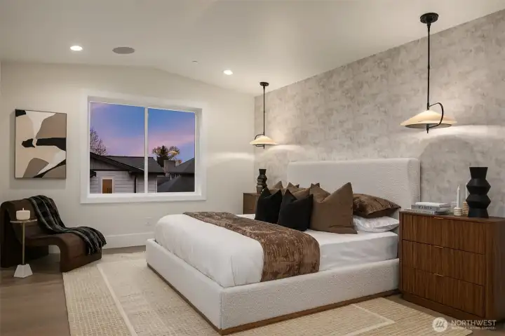 Light-filled primary bedroom highlighted by designer pendant lighting and a spacious layout.