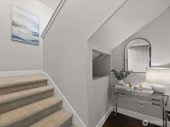 Entry staircase with vaulted ceiling, carpeted stairs, and interior landing with hardwood flooring