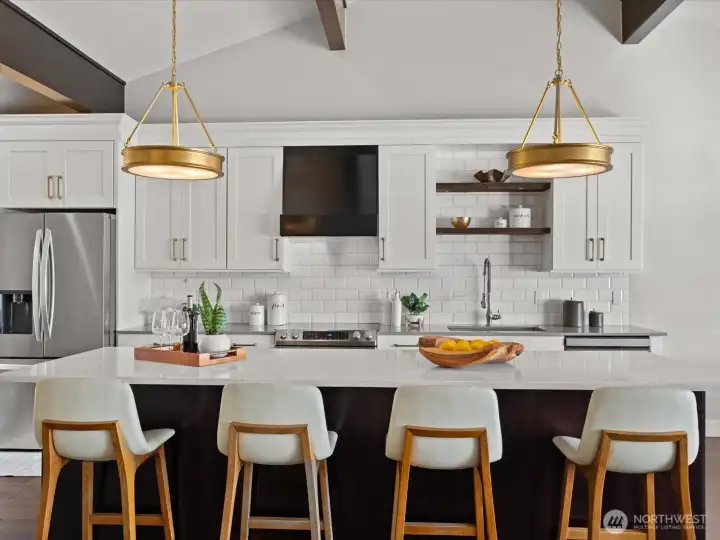 Kitchen with quartz countertops, island seating, tile backsplash, and stainless steel appliances